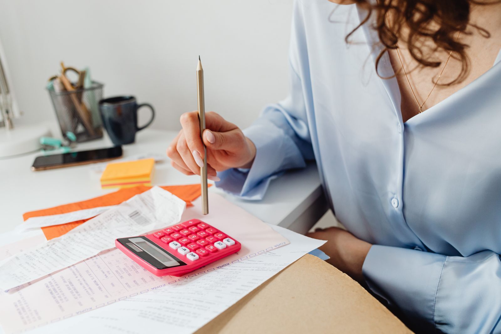 Empresária faz contas com calculadora e lápis sobre notas e papéis para decidir sobre o Simples Nacional híbrido